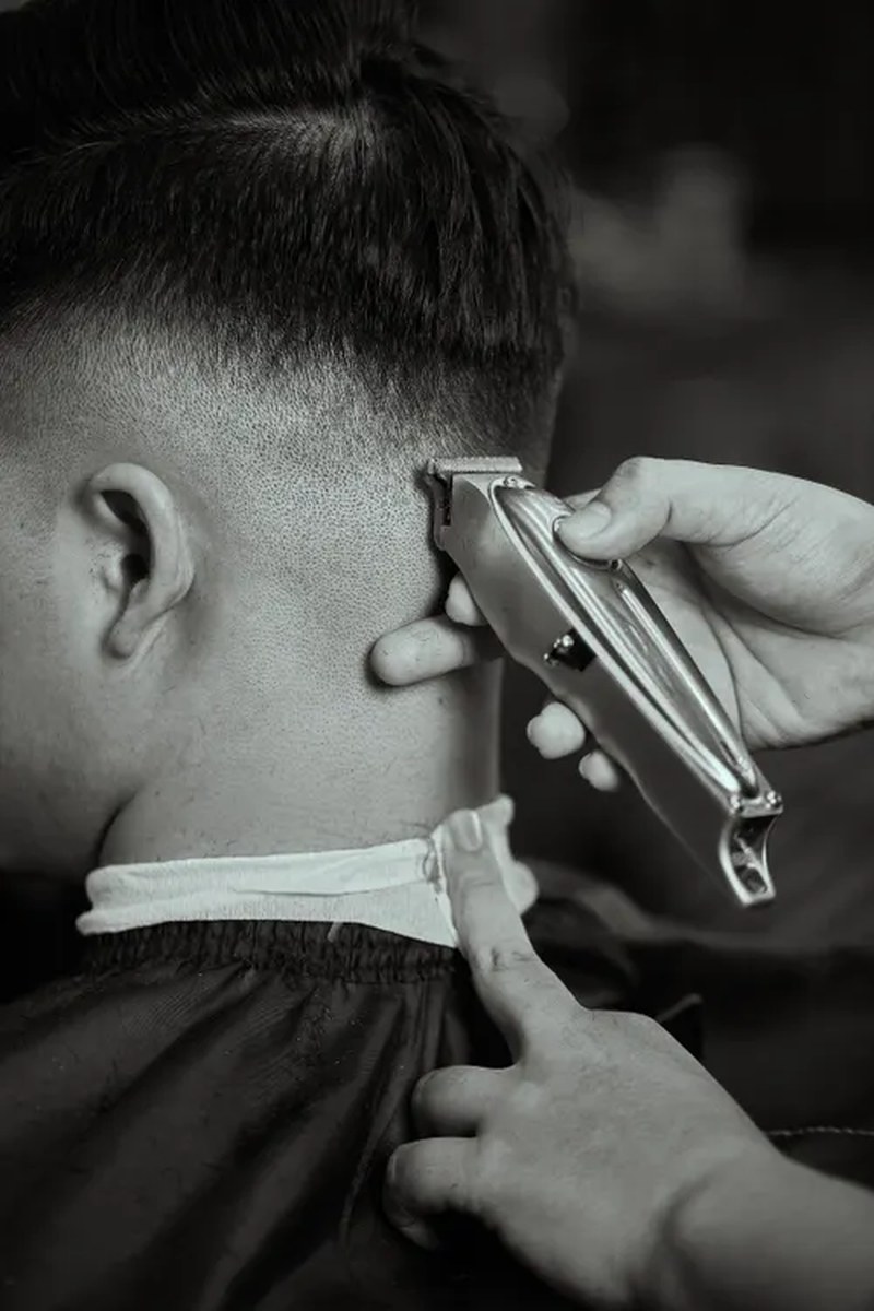 Monochrome close-up of a barber refining a taper fade
